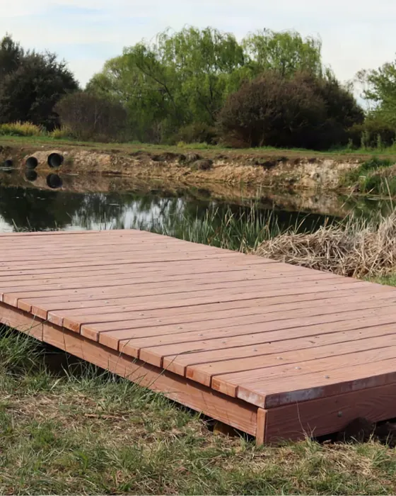 Hybrid Sleeper decking boards on a low platform beside a pond