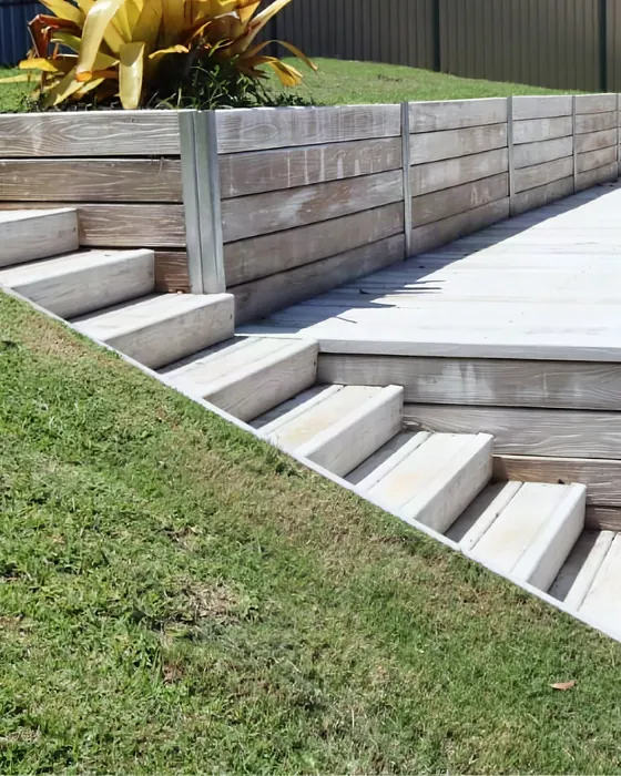 Pale grey Hybrid Sleeper stairs climbing a lawn beside a retaining wall