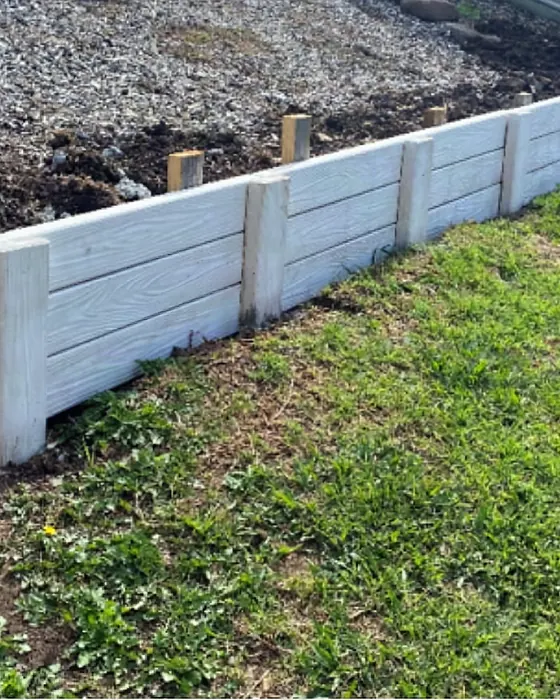 A low Hybrid Sleeper retaining wall with sleeper posts holding back a garden slope