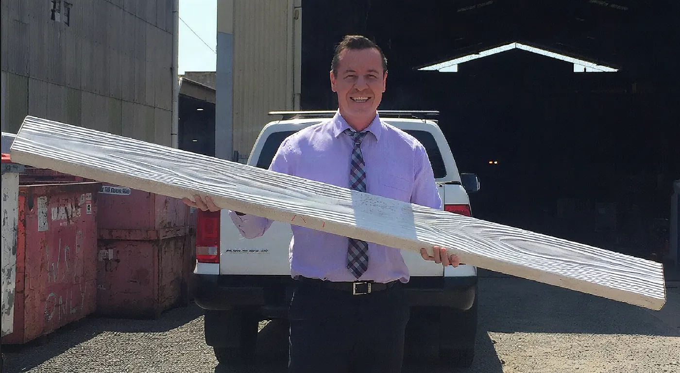A man holding a full-length pale grey Hybrid Sleeper at shoulder height in a factory yard
